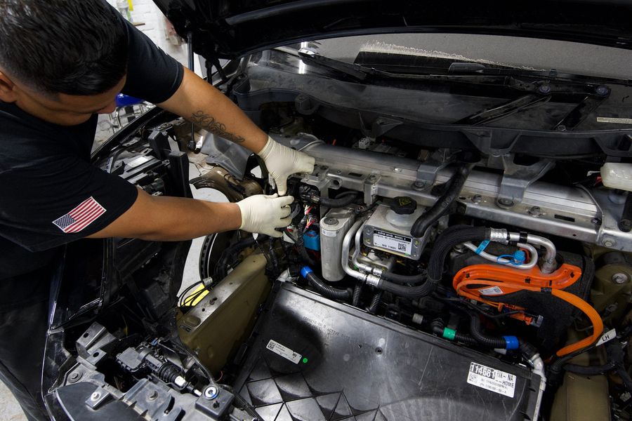 C & A Auto Body Shop technician working on the engine bay of a car