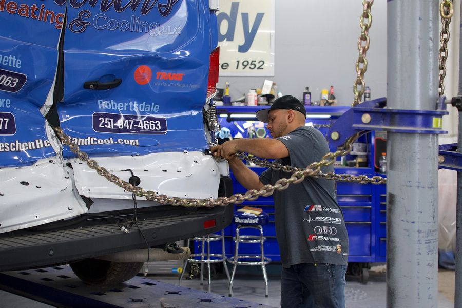 C & A Auto Body Shop technician chained to a frame rack for collision repair